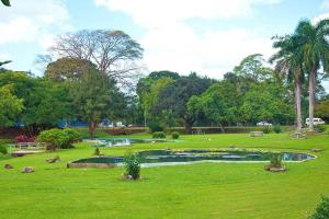 a park with a pond in the middle of a field at RayneBow Chateau - Chic City Getaway in Port-of-Spain