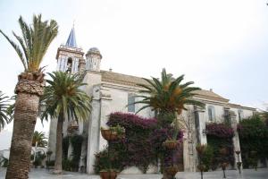 a building with palm trees and flowers in front of it at Hostal Gran Capitan in Chipiona