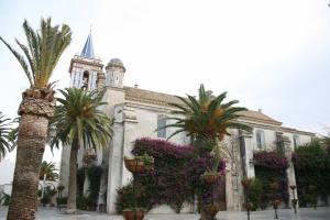 un edificio con palmeras y flores delante de él en Hostal Gran Capitan, en Chipiona