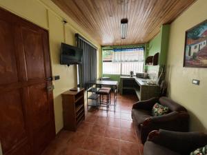 a living room with a couch and a table and a kitchen at Apartamento Sol Azul a 3 min del Aeropuerto SJO in Alajuela