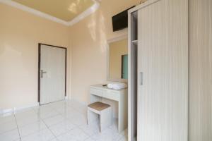 a white bathroom with a sink and a stool at Urbanview Hotel Nugraha Palembang by RedDoorz in Palembang