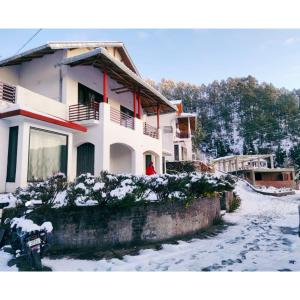 a house with a person standing outside in the snow at Just Naturals Wellness Resort Nainital in Bhowāli