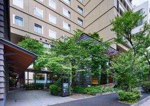 a large building with a tree in front of it at Hotel Niwa Tokyo in Tokyo