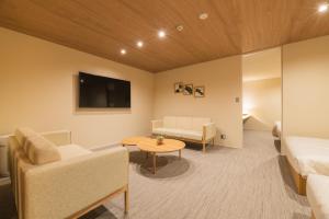 a room with a bed and a couch and a table at HOTEL All Stay Hakata Kukodori in Fukuoka