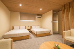 a hotel room with two beds and a table at HOTEL All Stay Hakata Kukodori in Fukuoka