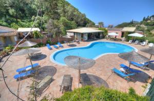a pool with chairs and umbrellas next to a resort at Paleo Apartments in Paleokastritsa