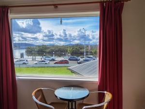 ein Fenster mit einem Tisch und Stühlen sowie Straßenblick in der Unterkunft Watersedge Motel in Woy Woy