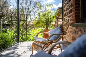 a pair of chairs sitting on a porch with a plant at Secret Garden - Luxury Cottage - Giant 85inch TV in McLaren Vale +38 photos