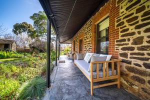 a patio with a couch on a brick wall at Secret Garden - Luxury Cottage - Giant 85inch TV in McLaren Vale