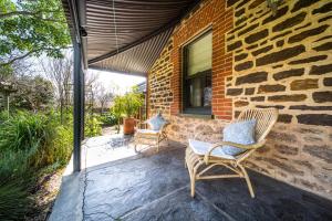 two chairs on a patio next to a brick wall at Secret Garden - Luxury Cottage - Giant 85inch TV in McLaren Vale