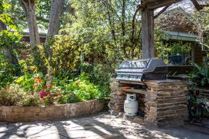 a grill in a garden with flowers and plants at Secret Garden - Luxury Cottage - Giant 85inch TV in McLaren Vale