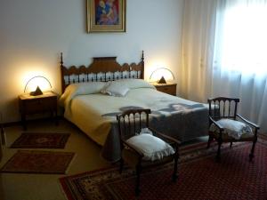 a bedroom with a large bed with two chairs at B&B Cà d'Artisti in Caorle