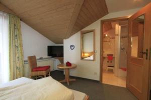 a bedroom with a bed and a table and a chair at Alpenlodge Pfronten in Pfronten