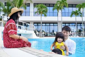 a woman and a man and a little girl sitting in a swimming pool at Southern Beach Hotel & Resort Okinawa in Itoman +158 photos