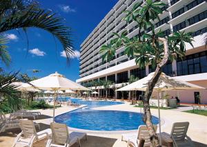 een zwembad met stoelen en parasols en een gebouw bij Southern Beach Hotel & Resort in Itoman