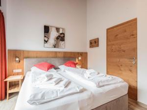 sypialnia z 2 łóżkami z białą pościelą i czerwonymi poduszkami w obiekcie Fantastic chalet with sauna w mieście Niedernsill