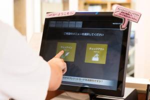 una persona está apuntando a una pantalla de ordenador en Wild Cherry Blossom-HOSTEL,TOKYO KOGANEI- en Koganei