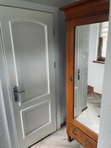 a door with a mirror next to a wooden cabinet at Domek u Danusi in Lubiatowo
