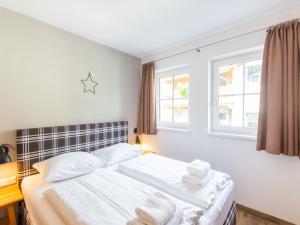 a bedroom with a bed with white sheets and two windows at Lush holiday home in Niedernsill with sauna in Niedernsill