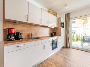 尼德恩西尔Holiday home in Niedernsill with sauna的一间厨房,配有白色的橱柜和大窗户