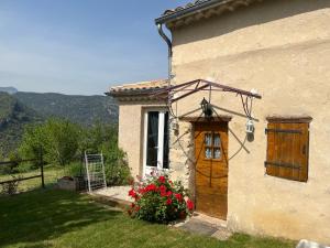 a building with a wooden door and flowers in front at Cabanon entouré de montagnes et d'oliviers in Nyons