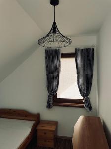 a bedroom with a bed and a window with a chandelier at Domek u Danusi in Lubiatowo
