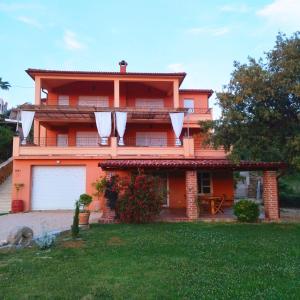 an orange house with a lawn in front of it at Apartments Villa Kristina in Supetarska Draga