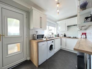 a kitchen with white cabinets and a washer and dryer at Dragonfly - HOT TUB luxury two bedroom cottage in Cellardyke