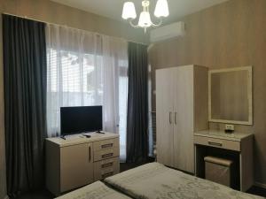 a bedroom with a bed and a desk and a television at Джорджия in Kiten +57 photos
