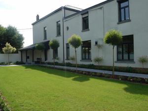 a large white building with a grassy area at Guesthouse Les Tilleuls in Fleurus