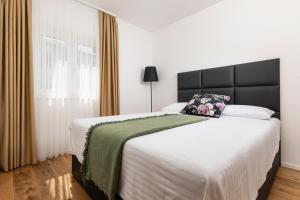 a bedroom with a large bed with a black headboard at Villa Pafran with heated pool Krk in Krk +48 photos