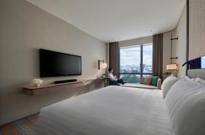 um quarto de hotel com uma cama grande e uma televisão de ecrã plano em Amari Kuala Lumpur em Kuala Lumpur