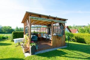 a wooden gazebo in a garden with a table at Ferienwohnungen Eva Lange in Uhldingen-Mühlhofen
