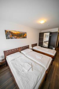 two twin beds in a bedroom with a painting on the wall at Leone Penzion&Restaurant in Harichovce