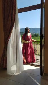 a woman in a pink dress standing on a balcony at Agriturismo Il Casale del Cavaliere in Sant'Agata de' Goti