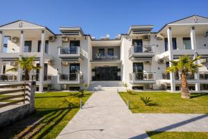 a large white building with palm trees in front of it at Villa MARIA in Nea Vrasna