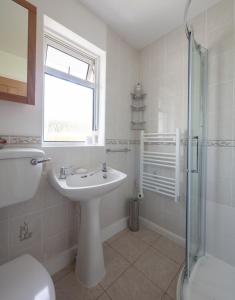 a white bathroom with a sink and a shower at ‘Sea Glimpse’ in the coastal Devon village of East Prawle in West Prawle