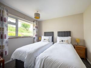 two twin beds in a bedroom with a window at ‘Sea Glimpse’ in the coastal Devon village of East Prawle in West Prawle