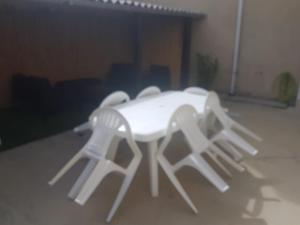 une table blanche entourée de trois chaises blanches dans l'établissement LA MAISON DE LOLA, à Port-en-Bessin-Huppain