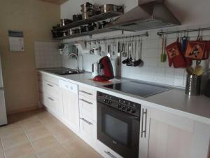 cocina con armarios blancos y fogones negros en Ferienwohnung Hilde Schneider, en Kappeln