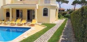 a villa with a swimming pool in front of a house at Vila Rosada in Quarteira