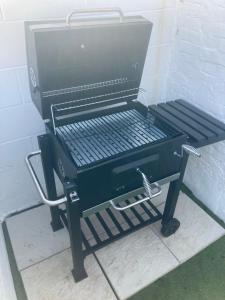 a charcoal grill sitting on a stand next to a wall at Pier Plain By The Sea in Gorleston-on-Sea