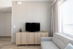 Arctic Penthouse City Suite في روفانييمي: غرفة معيشة مع أريكة وتلفزيون على خزانة