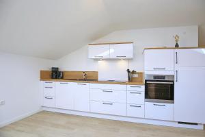 - une cuisine blanche avec des placards blancs et un évier dans l'établissement Strandvilla Meeresblick Wohnung 07, à Boltenhagen