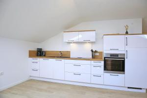 a white kitchen with white cabinets and a sink at Strandvilla Meeresblick Wohnung 07 in Boltenhagen