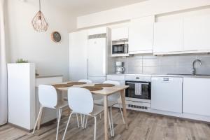 a kitchen with white cabinets and a table and chairs at Arctic Penthouse City Suite in Rovaniemi +6 photos