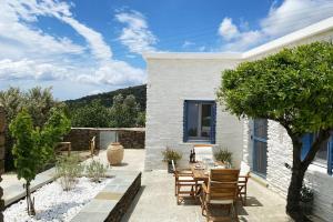 a patio with a table and chairs and a tree at Amarienitas Suites in Andros