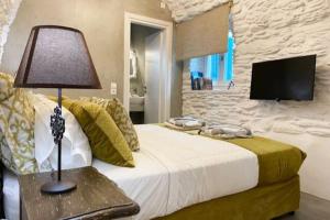 1 dormitorio con 1 cama con lámpara y TV en Amarienitas Suites, en Ándros