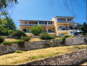 une maison jaune au-dessus d'un mur en pierre dans l'établissement Corfu island KASSIOPI’S best sea view apartment, à Kassiopi