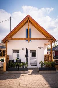 a small white house with a wooden roof at Neu Renoviertes Ferienhaus/wohnunng Kleine Auszeit in Sonnenbühl